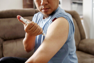 Diabetic young man using lancet pen at home