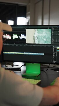 Vertical - male sit near computer screen and use video editing software