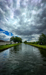 Fototapeta premium A serene canal scene with stunning reflections and moody clouds, ideal for nature and landscape themes