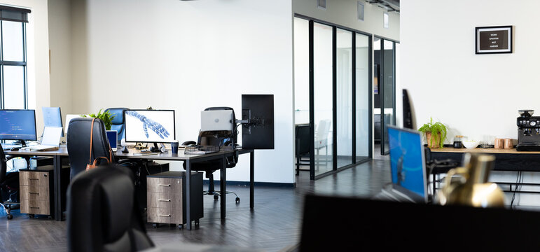 Modern office with multiple workstations and computers, featuring robotic arm