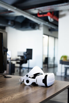 Virtual reality headset on desk in modern office, showcasing advanced technology, copy space