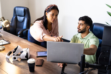 Discussing project, colleagues using laptop and VR headset in modern office