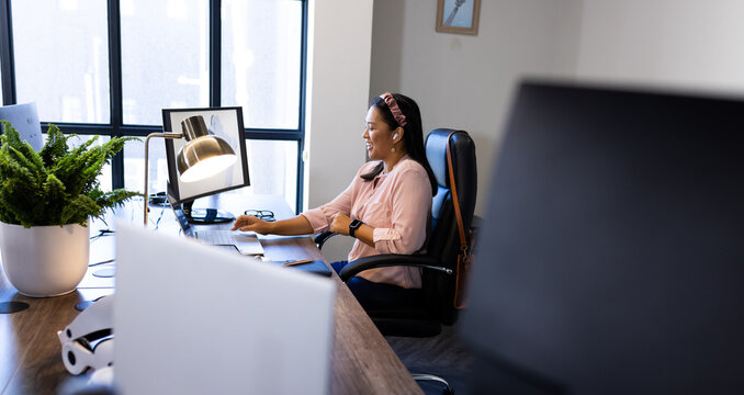 Working in modern office, woman using computer with robotic arm on desk