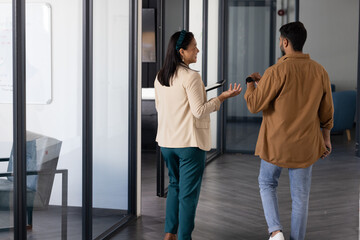 Walking through office, colleagues holding tablet and coffee cup, discussing work, copy space