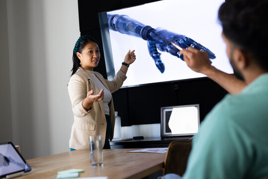 Presenting robotic technology, woman pointing at screen in modern office meeting