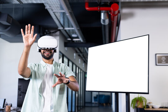 Using VR headset, Indian man interacting with virtual environment in modern office, copy space
