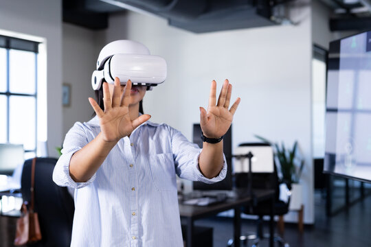 Using vr headset,  woman interacting with virtual environment in office setting, copy space