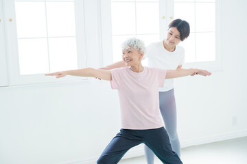 ヨガをするシニア女性とインストラクター