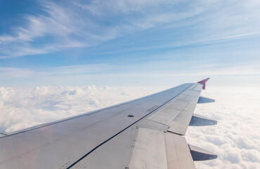 Fototapeta premium View from the airplane window at a beautiful cloudy sky and the airplane wing