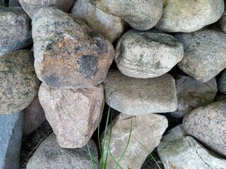 A man made stone wall, stacked stones, big stones creating pattern and texture