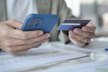 Asian Man paying with credit card on smart phone at office. Male Using Smartphone for Shopping electronic wallet Online