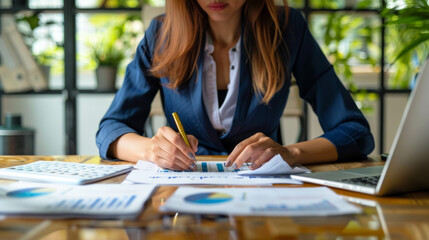 Fototapeta premium A professional woman analyzes data and takes notes in modern office setting, surrounded by charts and graphs.