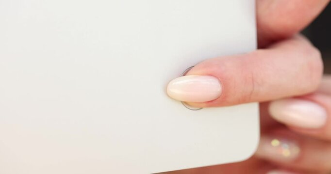 Closeup of finger pressing the power button on white device