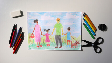Photo of child's drawing with pencils. Picture shows family. Mom, dad, boy, girl, dog are walking together. Mom of African American appearance. Dad is white. Pencils, scissors around. White background
