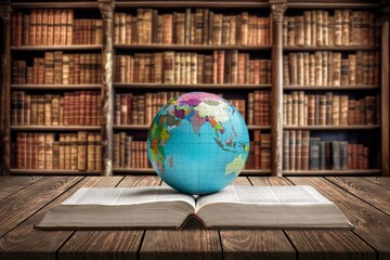 Old globe on open book in modern library.