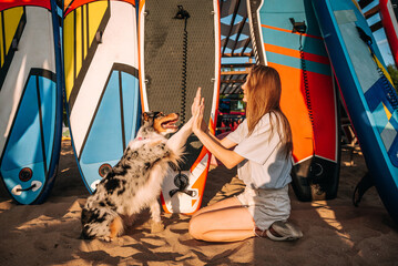 beautiful girl and smart cheerful funny tricolor dog Australian Shepherd on the surf beach relaxing...