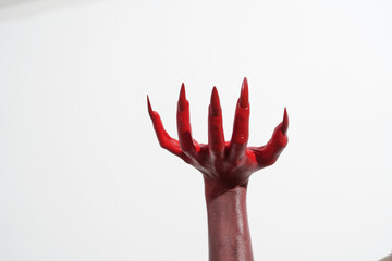 A witch's hand with long red nails on a white background, resembling a demon's or zombie's hand. This scary monster is perfect for Halloween, symbolizing a resurrected fictional creature.