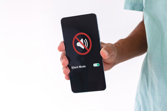 Man holding a smartphone with mute sound or silent mode symbol on the screen