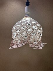 An intricate and delicate white lamp shade made with a Japanese art technique called mizuhiki