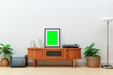 Modern wooden sideboard with blank green frame, vinyl player, and plants