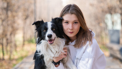 Caucasian woman hugging border collie in autumn park. Portrait of a girl with a dog.