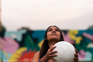 View of beautiful brunette female soccer player posing, holding and playing with soccer ball. On a...