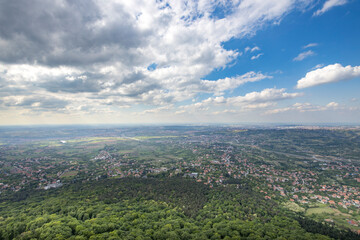 A city view with a cloudy sky and a green forest in the background