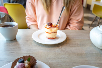 A woman is sitting at a table with a dessert in front of her