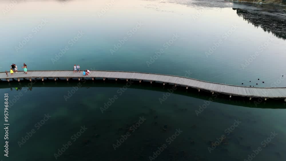 Poster Curved boardwalk extends over calm water at twilight creating a serene and tranquil scene