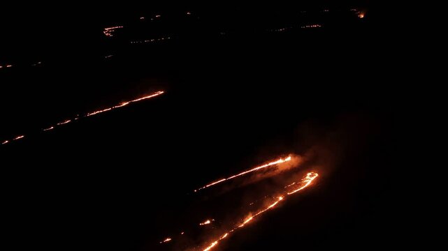 Raging fire at the dry grass meadow. Agricultural field fire burning. Night aerial footage of smoke and flame. Firefighters emergency response. Ecological catastrophe and environmental hazard.