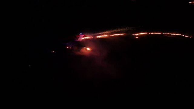Raging fire at the dry grass meadow. Agricultural field fire burning. Night aerial footage of smoke and flame. Firefighters emergency response. Ecological catastrophe and environmental hazard.
