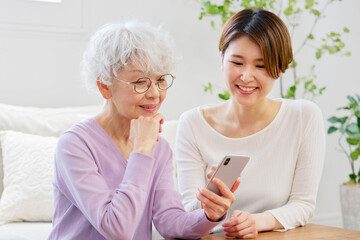 スマートフォンを使う母親と娘　リビングルーム