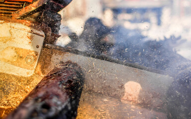 Powerful chainsaw cutting through wood at a busy construction site during the daytime. A chainsaw operates vigorously, sending sawdust flying in the air.
