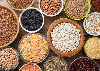 Bulgur,beans,quinoa,pea,couscous and hemp with chickpea and buckwheat seeds in various bowl plates on wooden kitchen background.Macro.