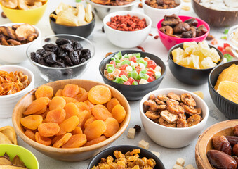 Mix of healthy dried sweet fruits and berries in various bowl plates on light kitchen background.Macro.