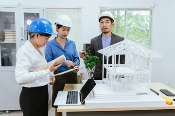 An office filled with a diverse team of professionals brainstorming and discussing computers and blueprints. An environment that showcases modern architecture and collaborative teamwork.