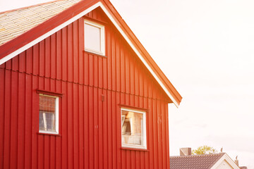 Red wooden house with vibrant roof against cloudy sky