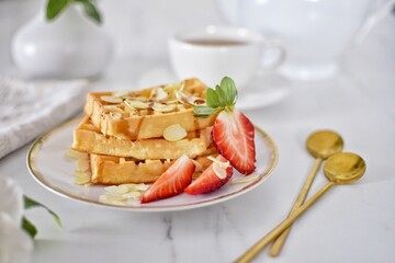 Viennese waffles with strawberries and syrup.