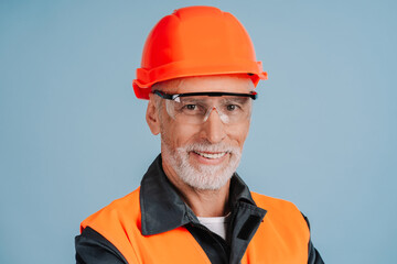 Smiling senior construction worker wearing hard hat and safety goggles