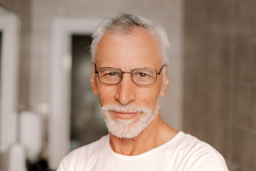 Senior man with white hair and beard smiling indoors