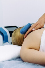 A doctor administers magnetic therapy to a young woman, targeting muscle recovery post-injury. Ideal for showcasing advanced physiotherapy treatments that accelerate healing and restore function.