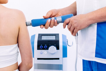 A physical therapist performs shock wave therapy with magnetic field assistance for targeted...