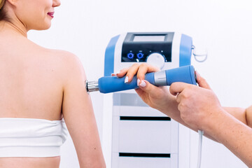 A physical therapist performs shock wave therapy with magnetic field assistance for targeted...