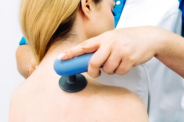 Naklejka premium A doctor administers magnetic therapy to a young woman, targeting muscle recovery post-injury. Ideal for showcasing advanced physiotherapy treatments that accelerate healing and restore function.