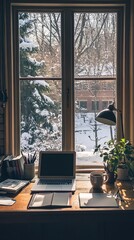 A laptop is on a desk next to a window with snow outside
