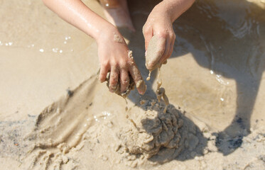 A girl plays in the sand on the seashore