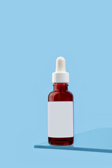 Mockup of cosmetic product anti-aging serum with retinol stot on glass shelf on blue background. Cosmetic product branding mockup. Daily skin care routine. Close-up.