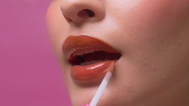 Close up of woman applying lip gloss on her sexy red lips. sensual with plump lips.