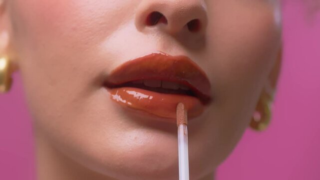 Beautiful woman applying lip gloss on her sexy red lips. sensual with plump lips.