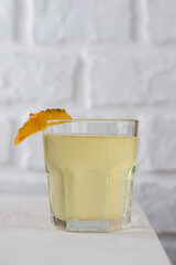 Pineapple kvass Tepache in a glass on a light table. Fermented, probiotic drink. Vertical orientation.